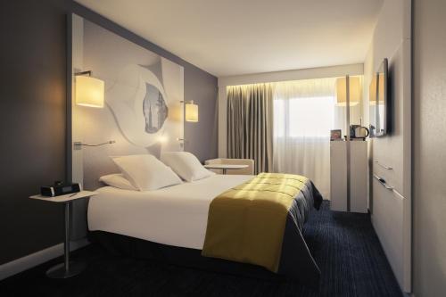 a hotel room with a bed and a lamp at Mercure Metz Centre in Metz