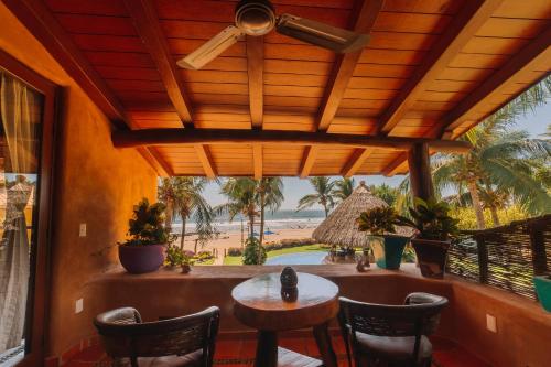 a porch with a table and chairs and a view of the beach at Tres Mujeres Hotel in Troncones