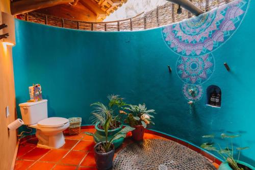a bathroom with a toilet and a blue wall at Tres Mujeres Hotel in Troncones