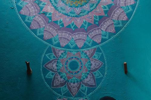 a painting of a mandala on a blue wall at Tres Mujeres Hotel in Troncones