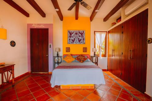 a bedroom with a bed in a room with orange walls at Tres Mujeres Hotel in Troncones