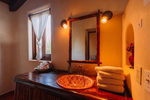 a bathroom with a sink and a mirror and towels at Tres Mujeres Hotel in Troncones