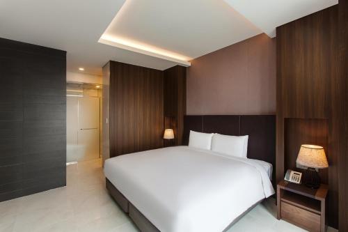 a bedroom with a large white bed and wooden walls at Hotel Adela in Busan