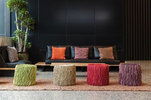 a black couch with colorful pillows on top of fourools at Hotel Adela in Busan