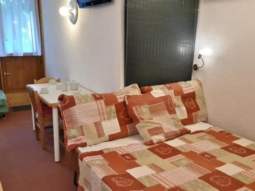 Cette chambre comprend un lit avec des oreillers et une table. dans l'établissement Studio au pied des pistes avec balcon et wifi - FR-1-346-503, à Arc 1800