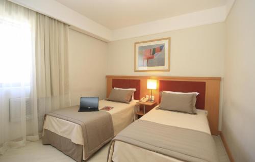 a room with two beds with a laptop on it at Bienal Suítes in Sao Paulo