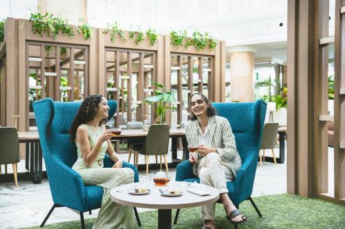 two women sitting in chairs in a restaurant at Oriental Hotel Okinawa Resort & Spa in Nago