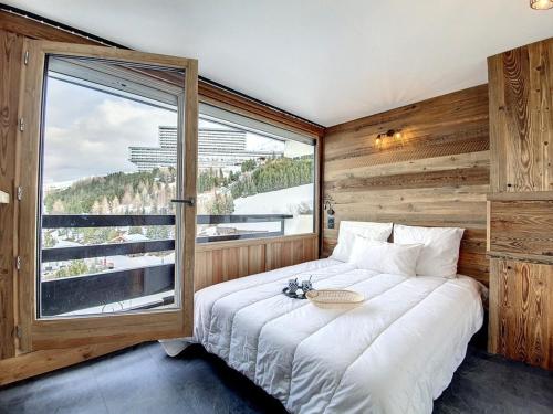un lit dans une chambre avec une grande fenêtre dans l'établissement Superbe appart rénové, balcon, au pied des pistes, style chalet, pour 8 pers - FR-1-344-735, aux Menuires