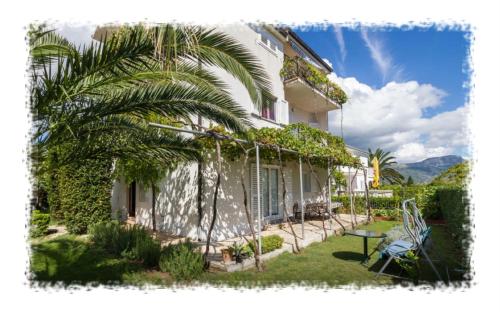 a house with a palm tree in front of it at Hostel Oktarin in Kaštela