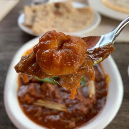 a spoon with a piece of food in a bowl of food at Ginger House Museum Hotel in Cochin