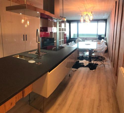 a kitchen with a black counter top and a table at Appartement "le chamois" la mongie centre 6 pers Bel appartement standing in La Mongie