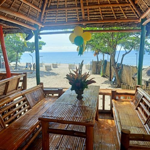 a wooden table with a potted plant on a beach at Shenanigans Glamping Resort in Zamboanguita