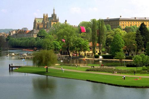 a park next to a body of water with a building at Mercure Metz Centre in Metz