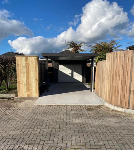 a house with a garage and a wooden fence at Central City Art Deco 2 bedroom House in Rotorua