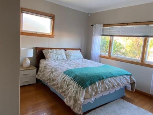 a bedroom with a bed and two windows at Central City Art Deco 2 bedroom House in Rotorua