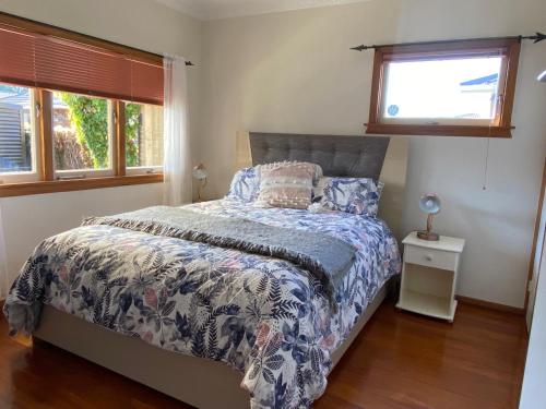 a bedroom with a bed and two windows at Central City Art Deco 2 bedroom House in Rotorua