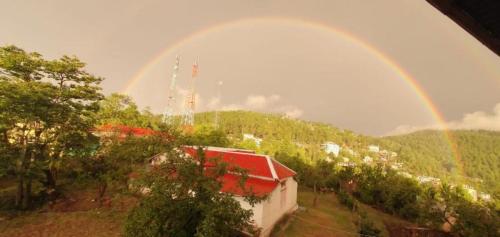 a rainbow over a house with a building at Shangrilla House Murree, Bhurban in Murree