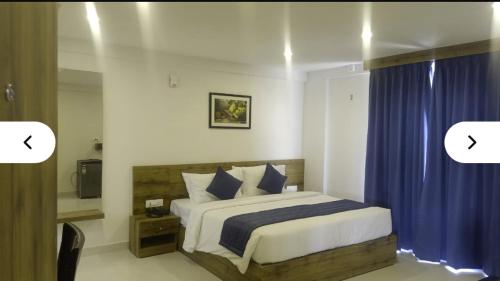 a bedroom with a large bed with blue curtains at Fly Inn in Bangalore