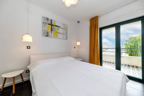 a white bedroom with a bed and a window at Mama House Villa in Novalja