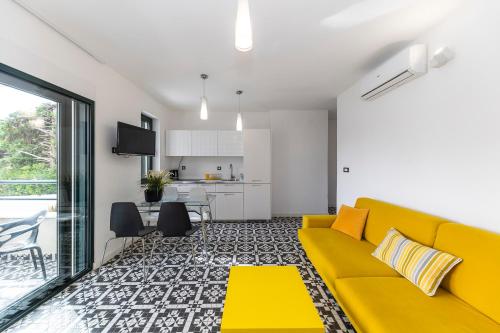 a living room with a yellow couch and a kitchen at Mama House Villa in Novalja