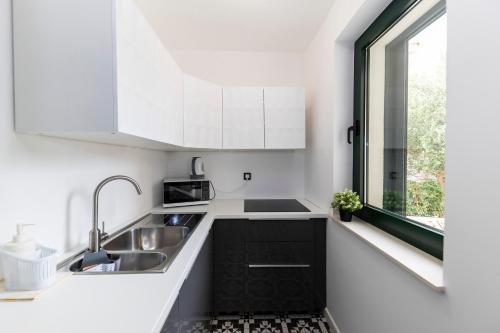 a white kitchen with a sink and a window at Mama House Villa in Novalja