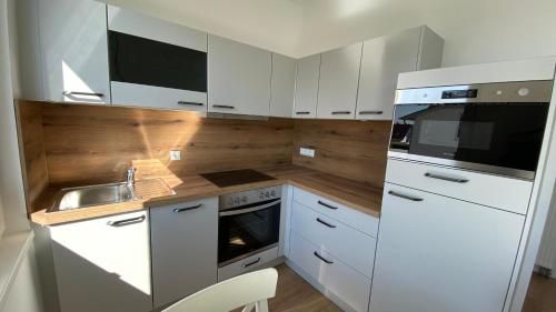 a small kitchen with white cabinets and a sink at Villa Rosalie Sassnitz in Sassnitz