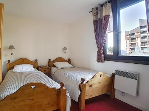 zwei Einzelbetten in einem Schlafzimmer mit Fenster in der Unterkunft Appartement 2 pièces près des pistes avec parking inclus - FR-1-344-797 in Les Menuires