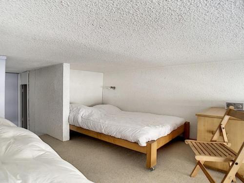 une petite chambre avec deux lits et une chaise dans l'établissement Duplex moderne avec balcon, ski aux pieds - FR-1-344-814, aux Menuires