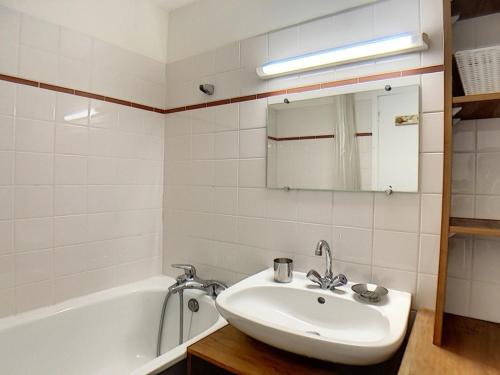 La salle de bains blanche est pourvue d'un lavabo et d'une baignoire. dans l'établissement Duplex moderne avec balcon, ski aux pieds - FR-1-344-814, aux Menuires