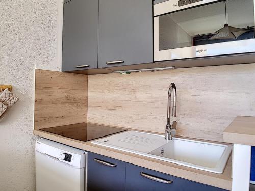 une cuisine avec un évier et un micro-ondes dans l'établissement Duplex lumineux skis aux pieds avec balcon - FR-1-344-827, aux Menuires