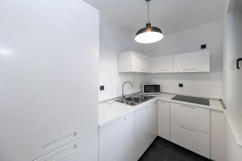 a white kitchen with white cabinets and a sink at Mama House Villa in Novalja