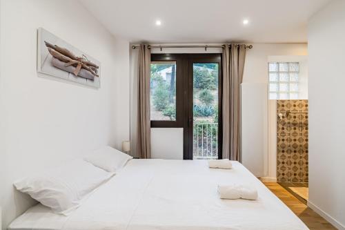 a white bedroom with a large bed and a window at Chez Jacques par Dodo-a-Cassis in Cassis