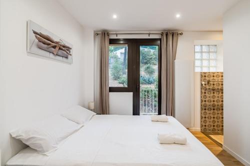een witte slaapkamer met een groot bed en een raam bij Chez Jacques par Dodo-a-Cassis in Cassis