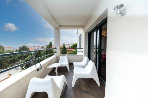 a balcony with white chairs and a view at Mama House Villa in Novalja