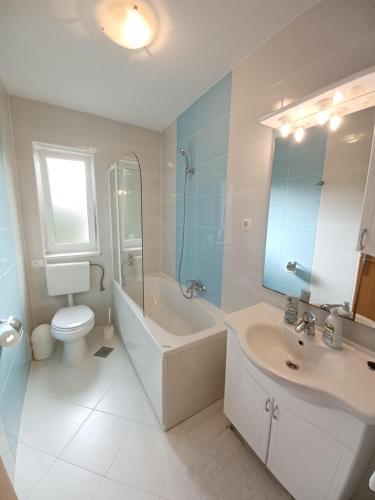 a bathroom with a sink and a tub and a toilet at Apartments Amor in Trogir