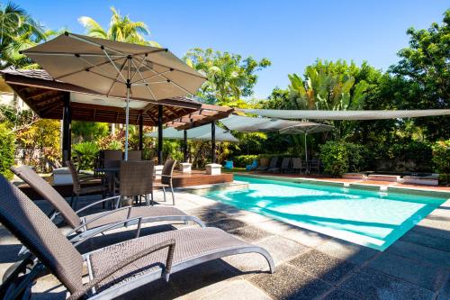 a swimming pool with chairs and umbrellas next to a swimming pool at The Mediterranean Port Douglas in Port Douglas
