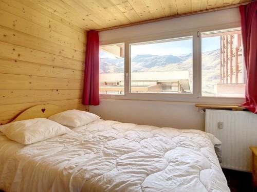un lit dans une chambre avec une fenêtre dans l'établissement Appartement rénové · Départ et retour ski aux pieds · 6 pers · Quartier La Croisette - FR-1-344-847, aux Menuires