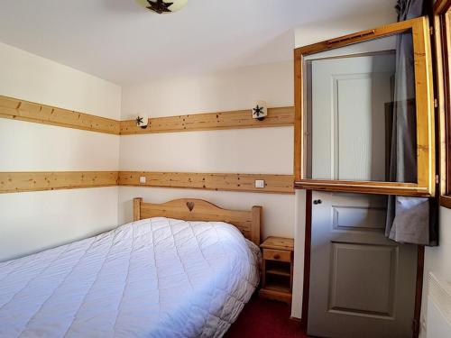 um pequeno quarto com uma cama e um espelho em Appartement Les Menuires, 3 pièces, 6 personnes - FR-1-344-849 em Levassaix