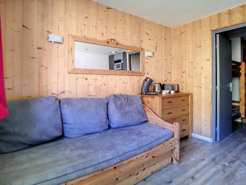- un canapé bleu dans une chambre dotée d'un mur en bois dans l'établissement Studio rénové avec balcon - Proche pistes et commerces - FR-1-344-872, aux Menuires