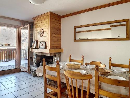 une salle à manger avec une table et une cheminée dans l'établissement Appartement spacieux, ski aux pieds, terrasse ensoleillée et parking privé - FR-1-344-886, aux Menuires