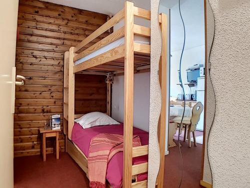ein hölzernes Etagenbett in einem Zimmer mit einem Tisch in der Unterkunft Appartement skis aux pieds avec balcon et parking - FR-1-344-880 in Les Bruyères