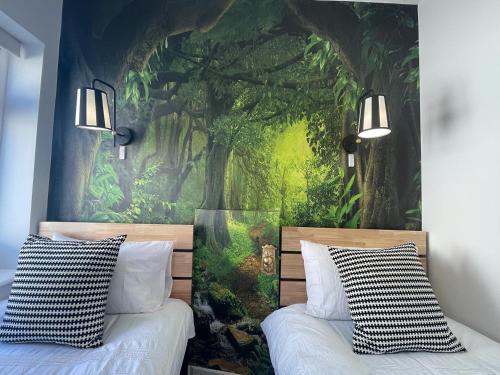 een slaapkamer met een bosmuurschildering aan de muur bij Coastline Retreats - Stunning Balcony Apartment with Sea Views - Alice in Wonderland Themed Secret Room - Luxury Copper Bath in Master Bedroom in Southbourne