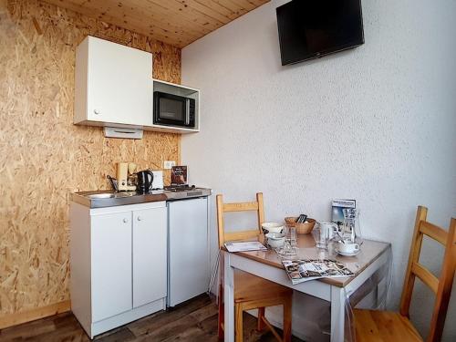 Il comprend une petite cuisine avec une table et un réfrigérateur blanc. dans l'établissement Studio 13m² pour 2 pers. - Pied des pistes et Centre station - 2 Flocons Argent - FR-1-344-876, aux Menuires