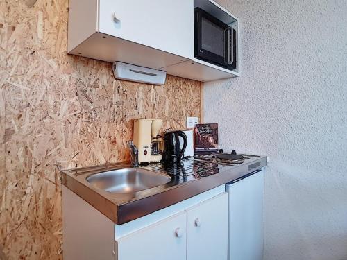 une petite cuisine avec un évier et un micro-ondes dans l'établissement Studio 13m² pour 2 pers. - Pied des pistes et Centre station - 2 Flocons Argent - FR-1-344-876, aux Menuires