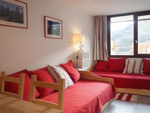 - un salon avec un canapé rouge et une fenêtre dans l'établissement Appartement cosy rénové 2 pièces - Skis aux pieds - Balcon sud-ouest - Centre resort - FR-1-344-877, aux Menuires