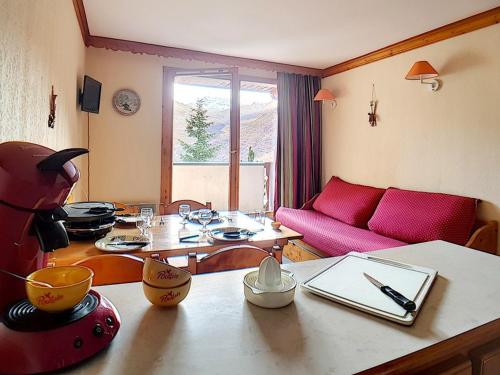 a living room with a table and a red couch at Appartement 2 pièces, Départ ski aux pieds, Balcon sud - FR-1-344-904 in Les Bruyères