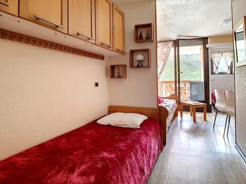 une chambre avec un lit avec une couverture rouge dans l'établissement Appartement lumineux Départ ski aux pieds Terrasse - FR-1-344-912, aux Menuires