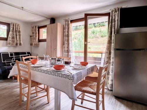 une cuisine avec une table avec des chaises et un réfrigérateur dans l'établissement Appartement confortable Proche des pistes Balcon Casier à skis - FR-1-344-916, aux Menuires