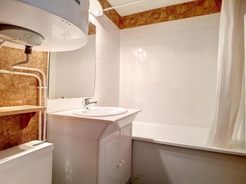 une salle de bain blanche avec un lavabo et une baignoire dans l'établissement Studio lumineux avec accès direct aux pistes et balcon - FR-1-344-917, aux Menuires