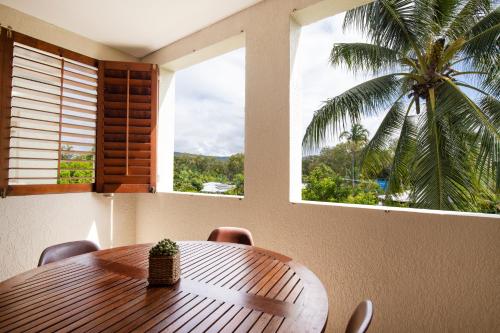 a wooden table and chairs in a room with a palm tree at The Mediterranean Port Douglas in Port Douglas